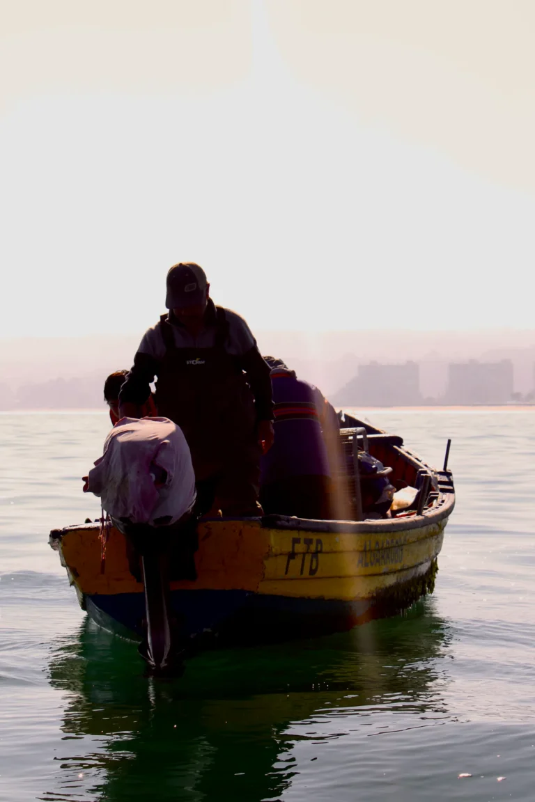 Dos personas en un pequeño bote sobre el mar calmo al amanecer